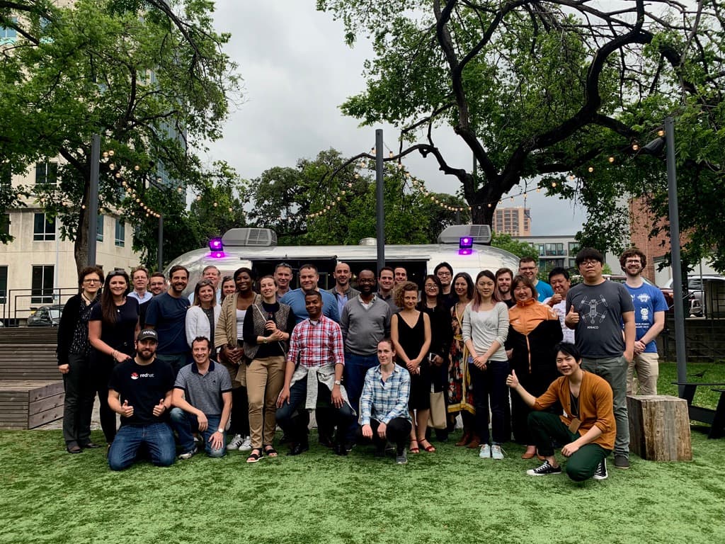 Arm Innovator Program members in a group photo on artificial turf, in front of a silver Airstream trailer under string lights