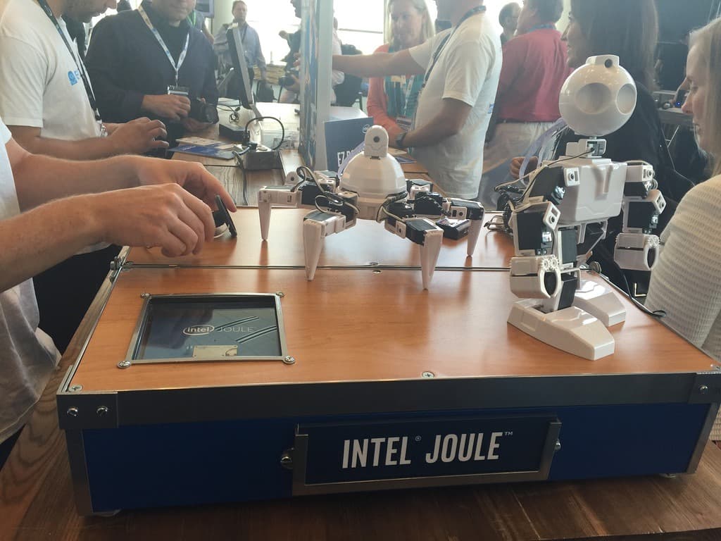 Two Joule-powered robots, a hexapod and a humanoid, on the Intel Joule demo table with a cutaway module under glass